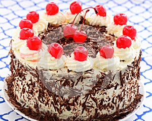 Blackforest gateau decorated with the traditional cream, chocolate flakes and cherries photo