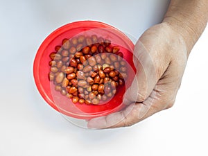 Blackish brown fried peanuts in a red container