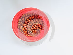 Blackish brown fried peanuts in a red container