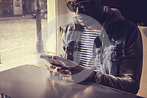 Blackman in sunglasses using smartphone.