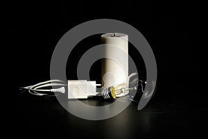 Blackout concept. Electric charger with cable near lighting candle on dark background