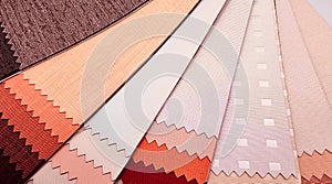 blackout drapery samples with different textures in soft red, orange, pink color tone, close up view.