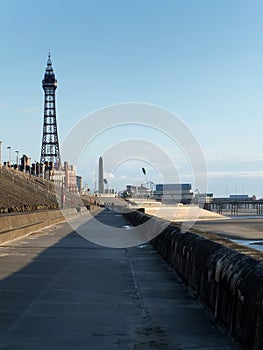Blackpool tower and south pier from the promenade with town buildings in afternoon sunlight