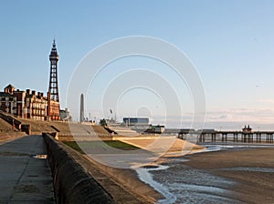 Blackpool tower and south pier from the promenade with town buildings in afternoon sunlight
