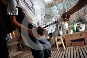 A blacksmith adds a hot shoe onto horse hoof feet