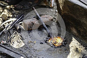 A blacksmith is burning hot iron. To hit and repair roadside iron equipment on a sidewalk in Sarnath, India