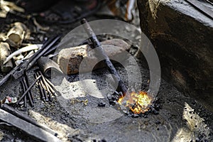 A blacksmith is burning hot iron. To hit and repair roadside iron equipment on a sidewalk in Sarnath, India