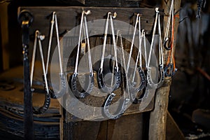 Blacksmith decorative horseshoes elements hanging at forge, workshop. Handmade, craftsmanship and blacksmithing