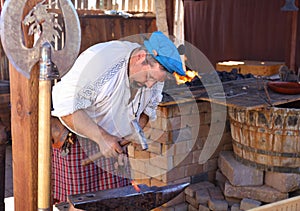 A Blacksmith Dressed in Traditional Outfit Forges Red Hot Metal into Swords