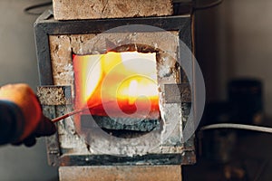 Blacksmith forge oven with hot flame. Smith heating iron piece of steel in fire of red-hot forge