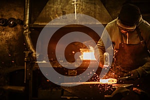 The blacksmith forging the molten metal on the anvil in smithy