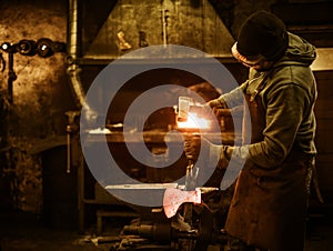 The blacksmith forging the molten metal on the anvil in smithy