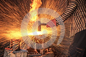 Blacksmith forging the molten metal with a hammer to make keris photo