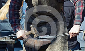 A blacksmith giving a demonstration of forging on an anvil.