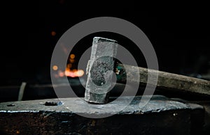 Blacksmith hammer on the anvil against the background of fire