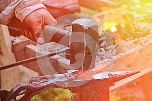 Blacksmith hammer hits the hot metal. Forging of iron objects in a retro forge. The process of working on the manufacture of