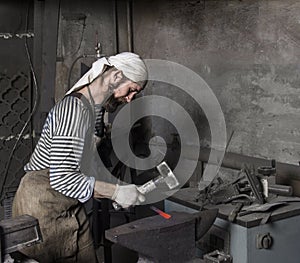 Blacksmith hammering a hot metal rod