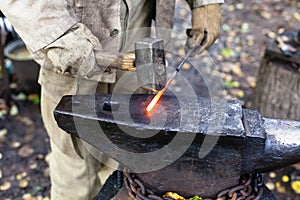 Blacksmith hammering hot steel rod on anvil