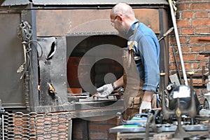 Blacksmith heats iron in a furnace. young traditional Blacksmith working with open fire The blacksmith making flames in smithy