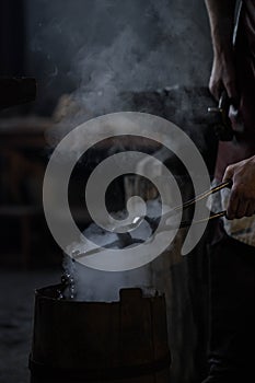 blacksmith holding iron work in forge