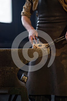 blacksmith holding iron work in forge