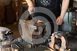 Blacksmith manually forging on iron on anvil at forge. Treatment of molten metal close-up