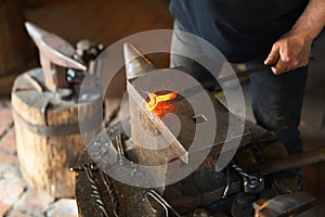 Blacksmith manually forging on iron on anvil at forge. Treatment of molten metal close-up