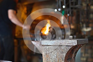Blacksmith manually forging on iron on anvil at forge. Treatment of molten metal close-up