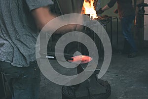 The blacksmith manually forging the molten metal on the anvil -