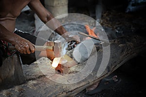 Blacksmith manually forging the molten metal on the anvil
