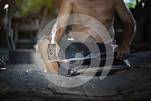 Blacksmith manually forging the molten metal on the anvil