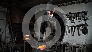 Blacksmith manually forging molten metal on anvil