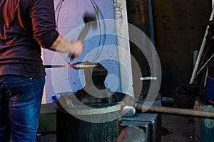 The blacksmith manually forging the molten metal on the anvil