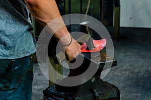 The blacksmith manually forging the molten metal on the anvil