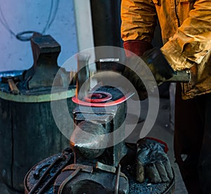 The blacksmith manually forging the molten metal on the anvil