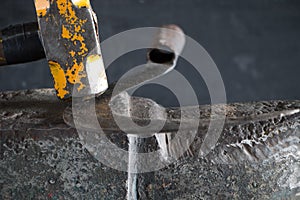 The blacksmith manually forging the molten metal on the anvil in