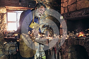 Blacksmith manually forging the molten metal on the anvil in photo