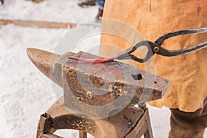 Blacksmith manually forging the molten metal on the anvil outdoors