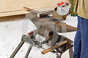 Blacksmith manually forging the molten metal on the anvil outdoors