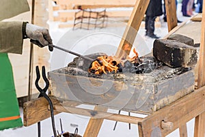 Blacksmith manually forging the molten metal on the anvil outdoors