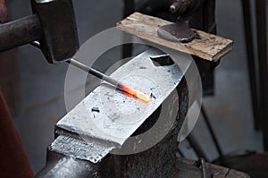 The blacksmith manually forging the molten metal on the anvil in smithy