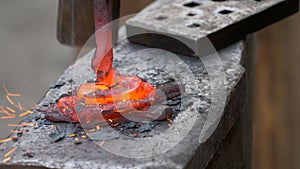 The blacksmith manually forging the molten metal on the anvil in smithy