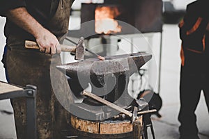 The blacksmith manually forging the molten metal on the anvil in smithy with spark fireworks, artwork