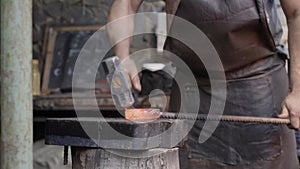 Blacksmith manually forging the molten metal. Close up of the hammer striking