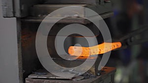Blacksmith nipping a hot metal rod by machine