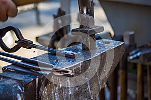 blacksmith performs the forging of hot glowing horseshoe on the anvil