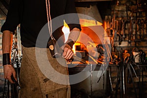 blacksmith performs the forging of hot glowing metal on the anvil