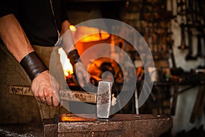 blacksmith performs the forging of hot glowing metal on the anvil