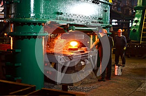 Blacksmith processes the red hot iron under a huge press. Metal forging, stamping under hammer forge at workshop of forge foctory