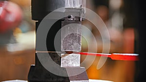 Blacksmith putting a longer piece of metal under the pressure of industrial forging machine